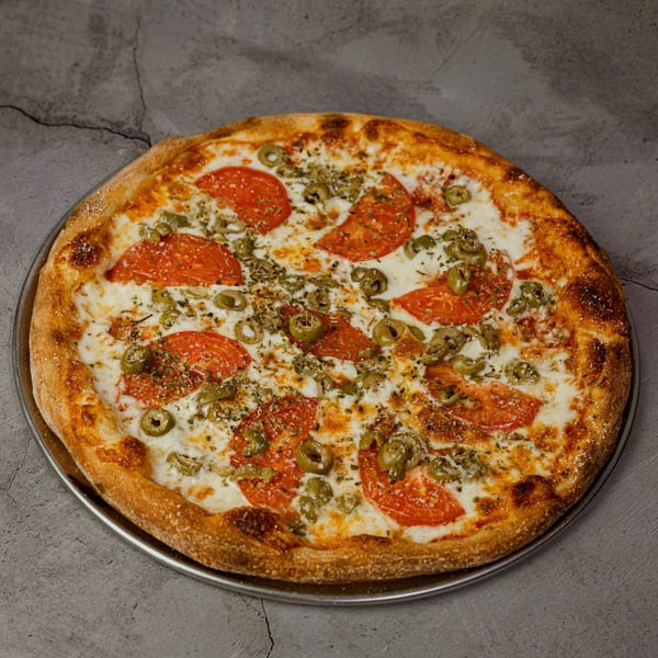 All Star Pizza & Pasta's pizza with tomatoes, green olives, and herbs on a gray background.